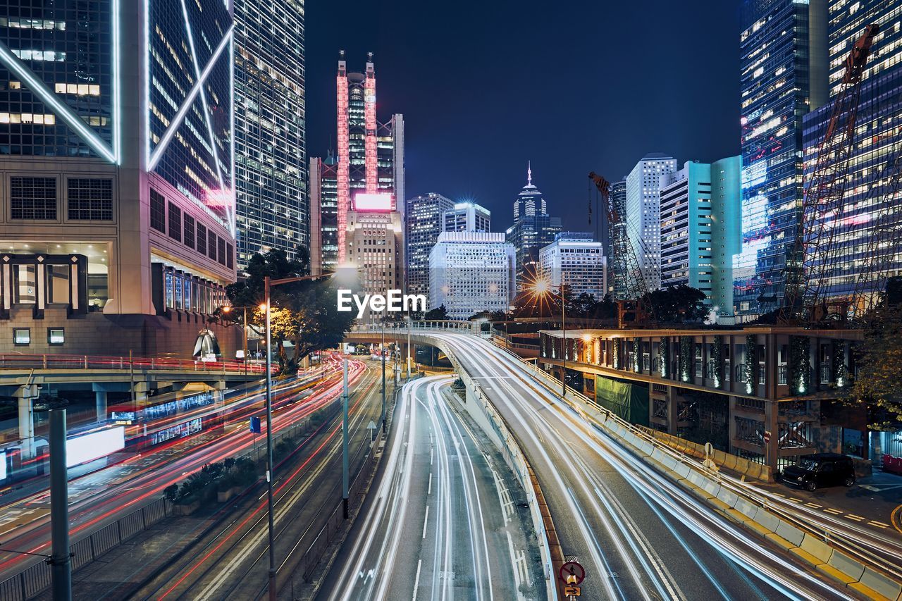 Light trails on road amidst buildings in city at night