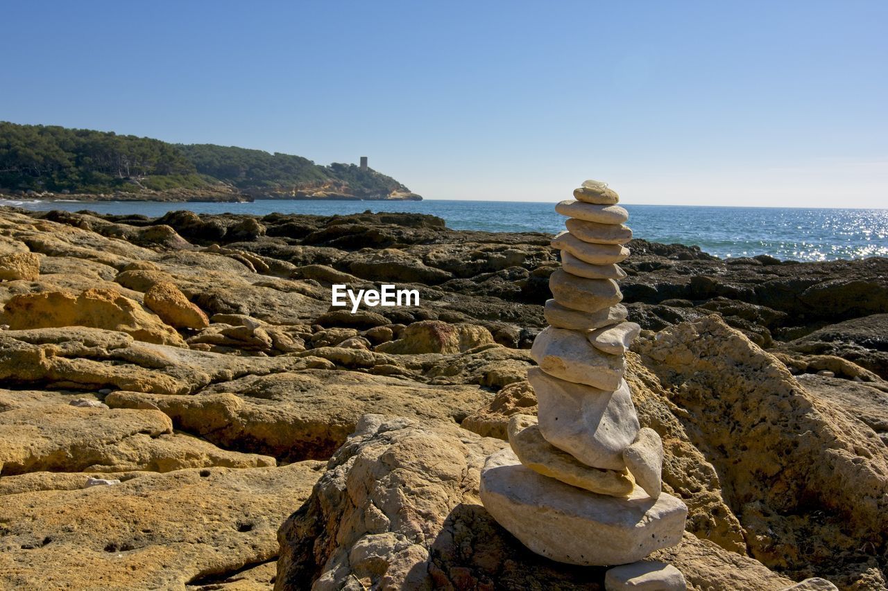 STACK OF ROCKS ON BEACH AGAINST SKY