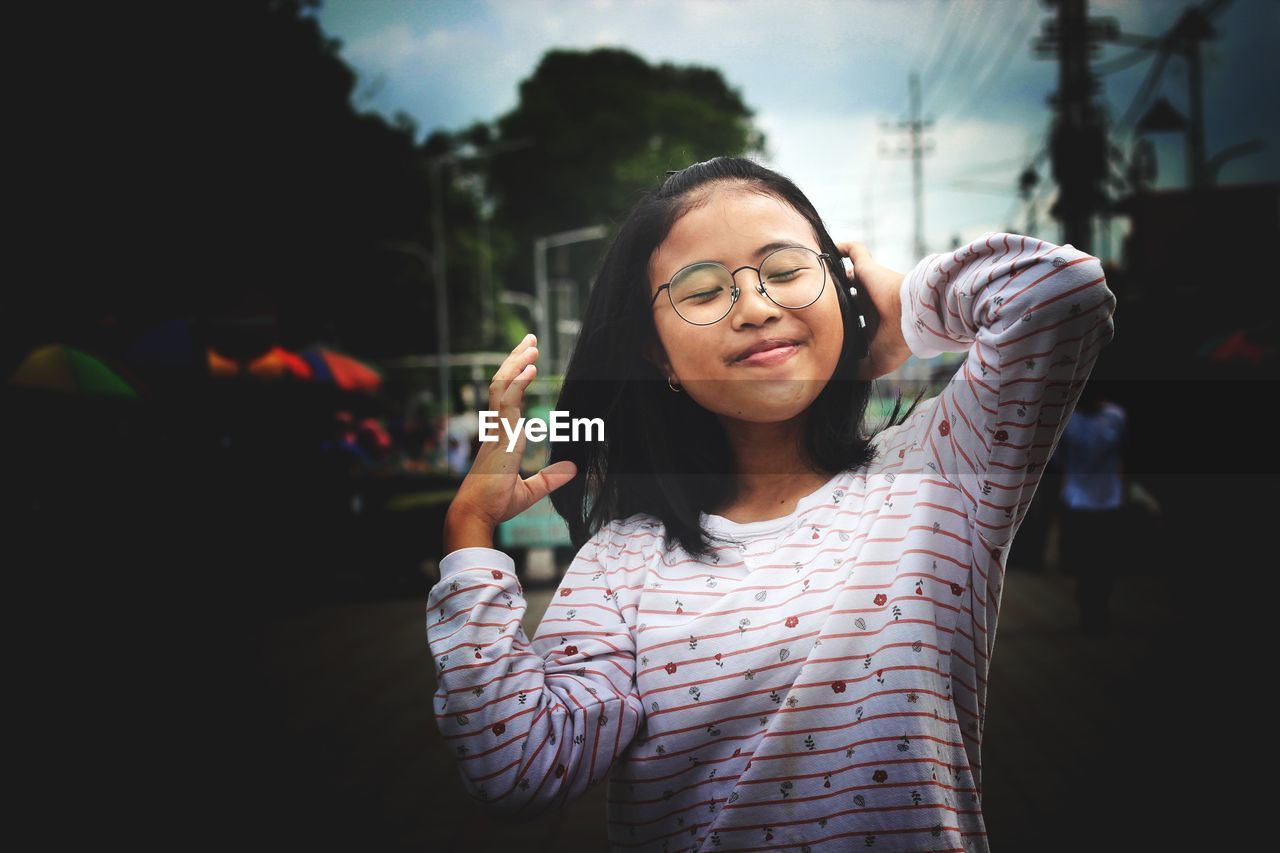 Smiling girl with eyes closed wearing eyeglasses outdoors