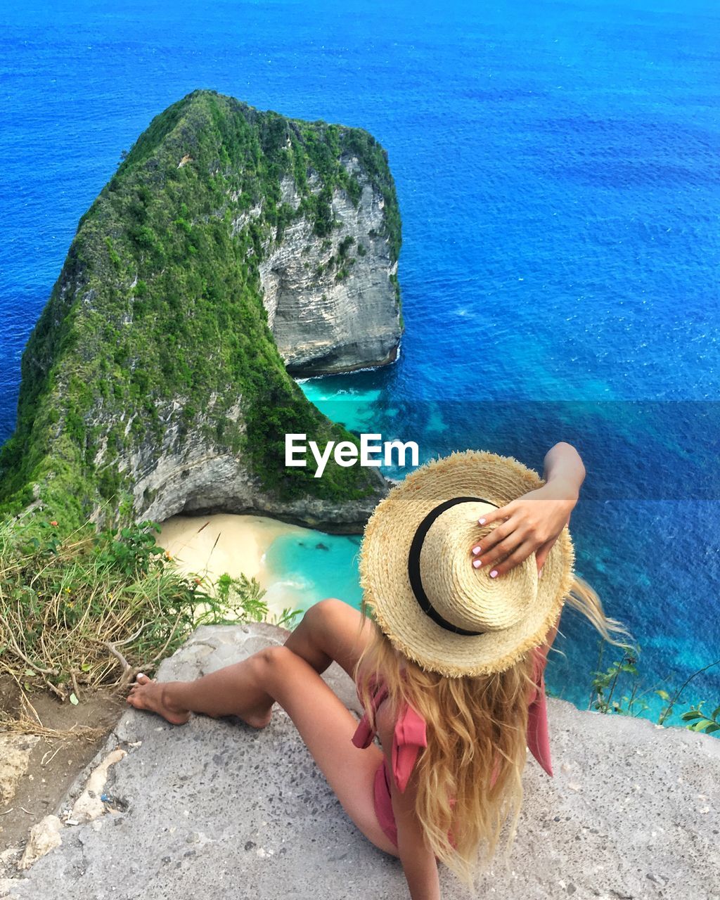 High angle view of woman sitting on cliff by sea