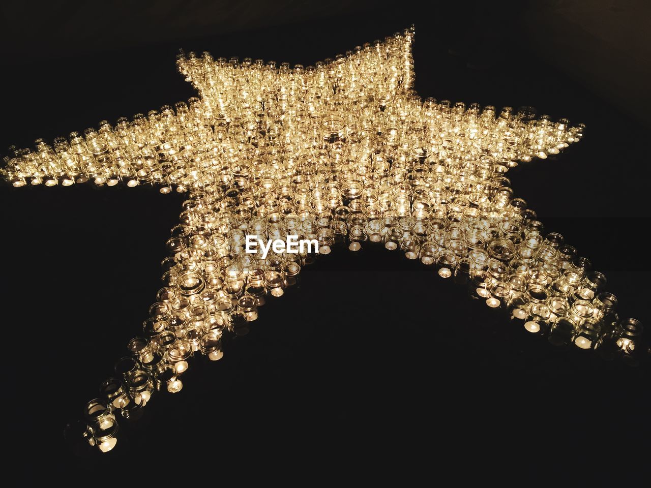 High angle view of illuminated tea lights in star shape over black background