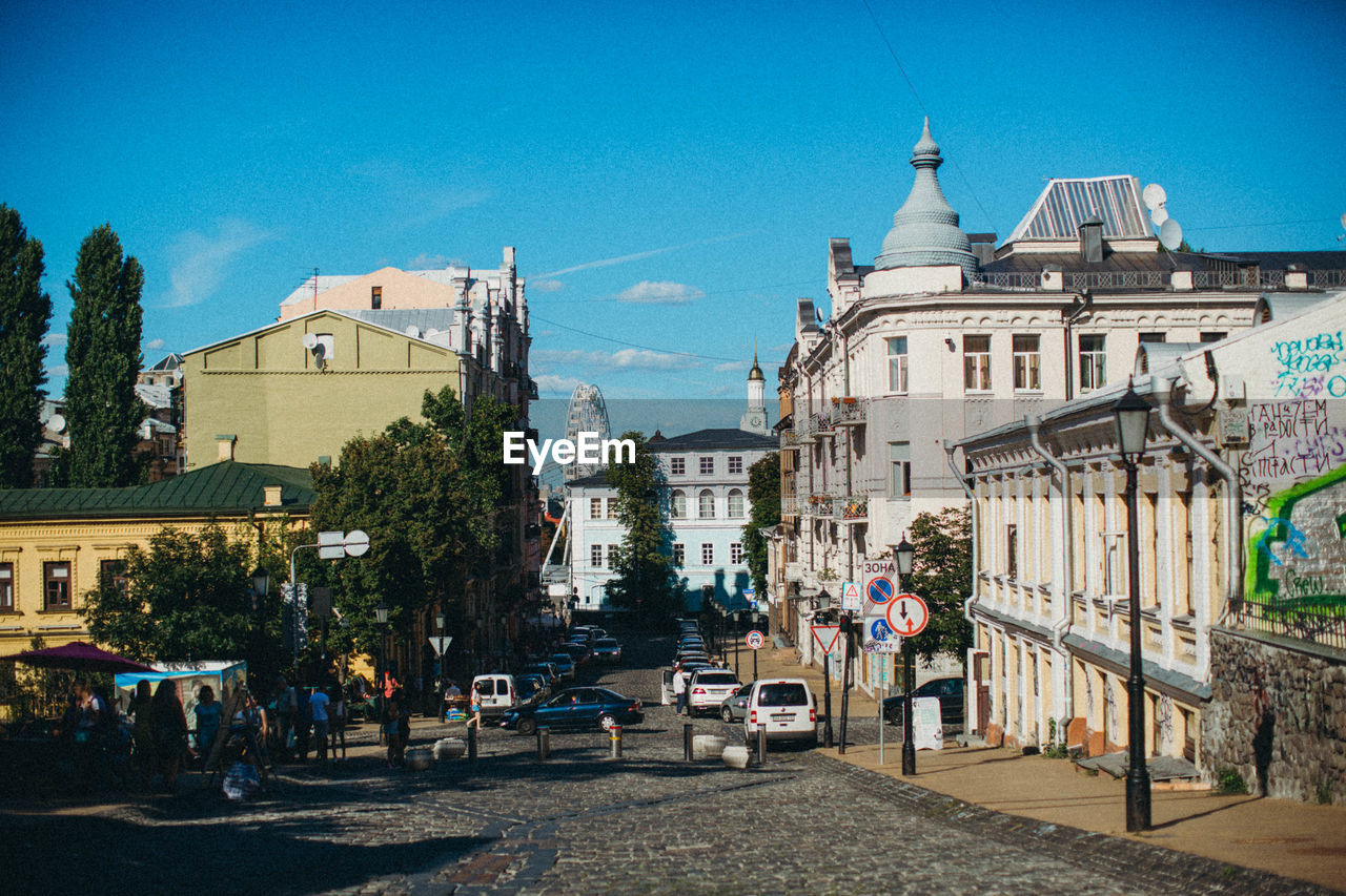 ROAD BY BUILDINGS AGAINST BLUE SKY