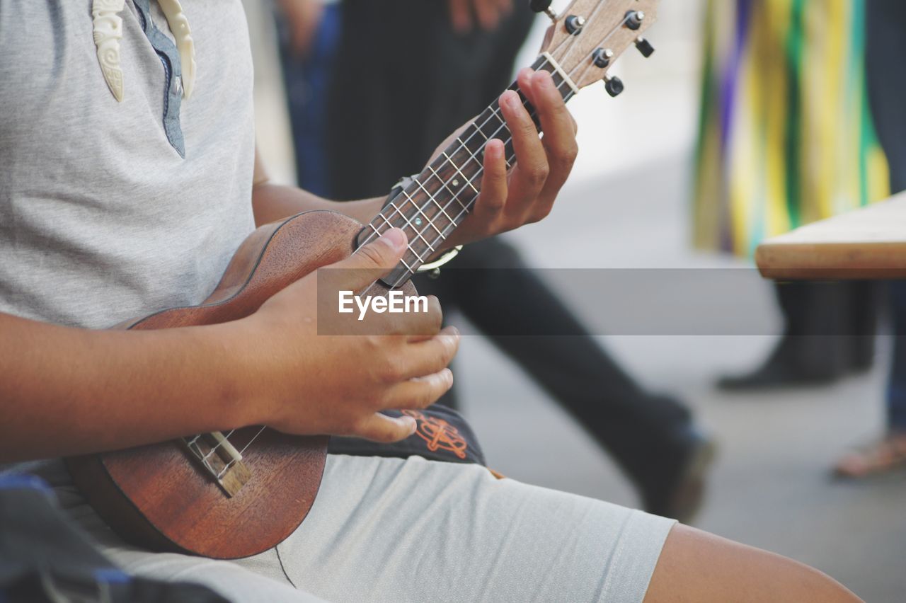 Midsection of man playing ukulele