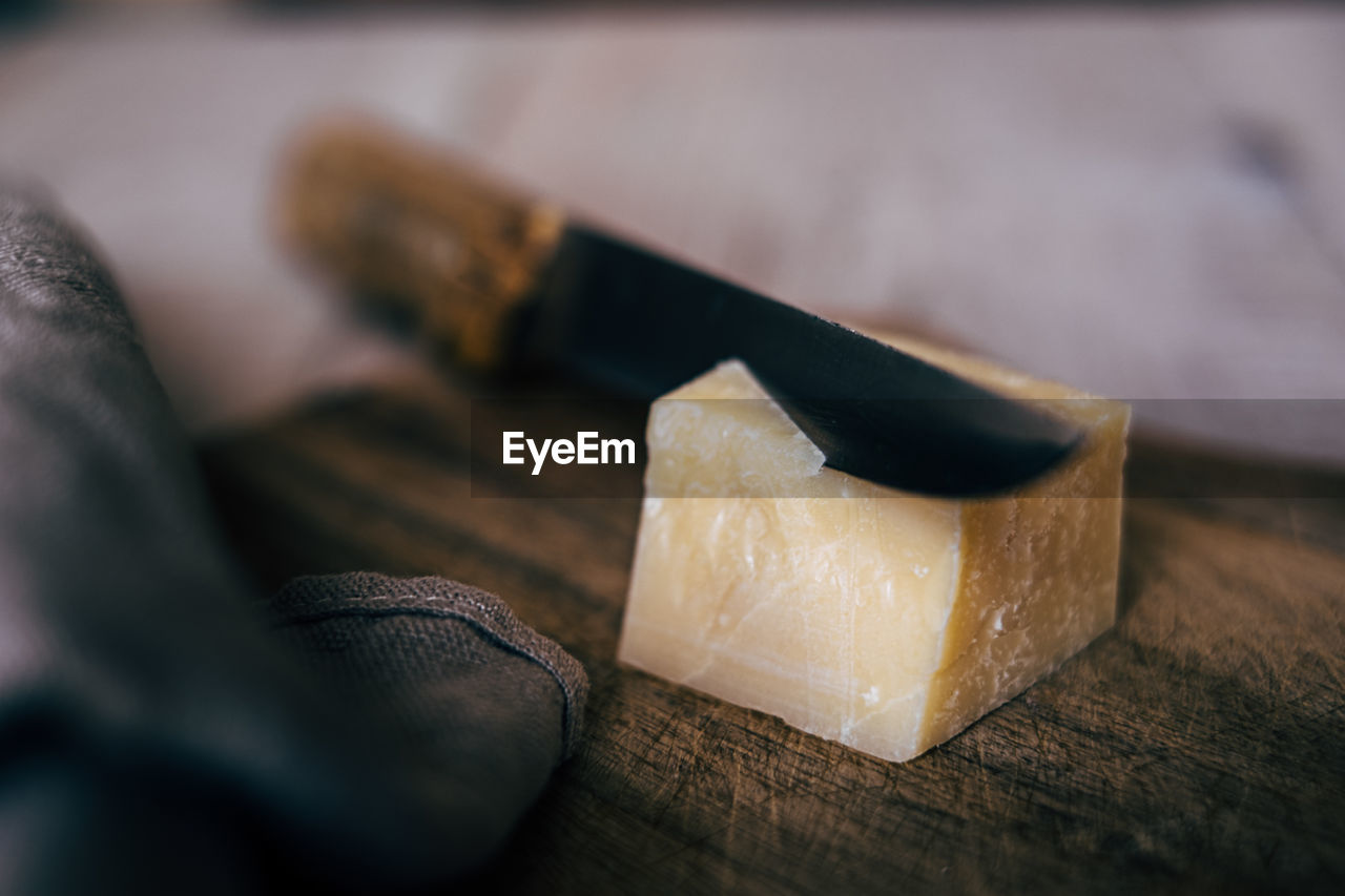 High angle view of knife cutting italian cheese on wooden board