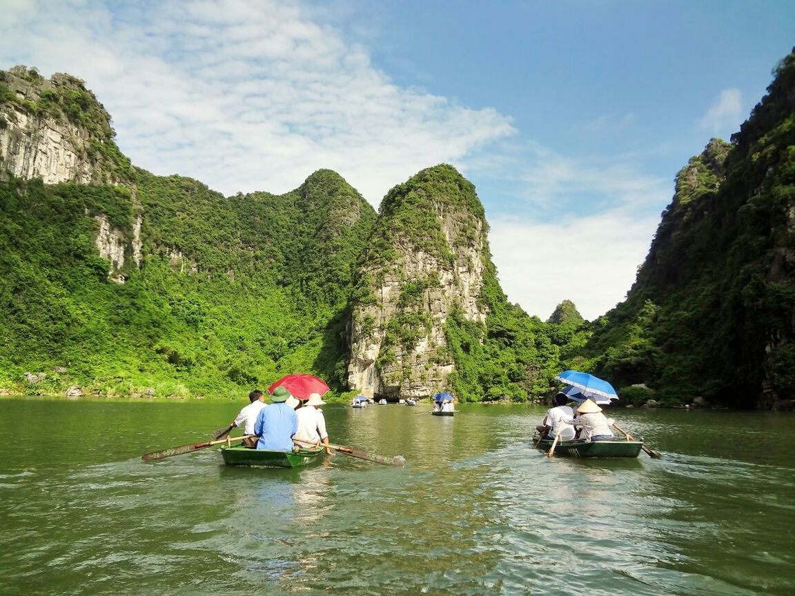 People rowing boat in lake against mountain