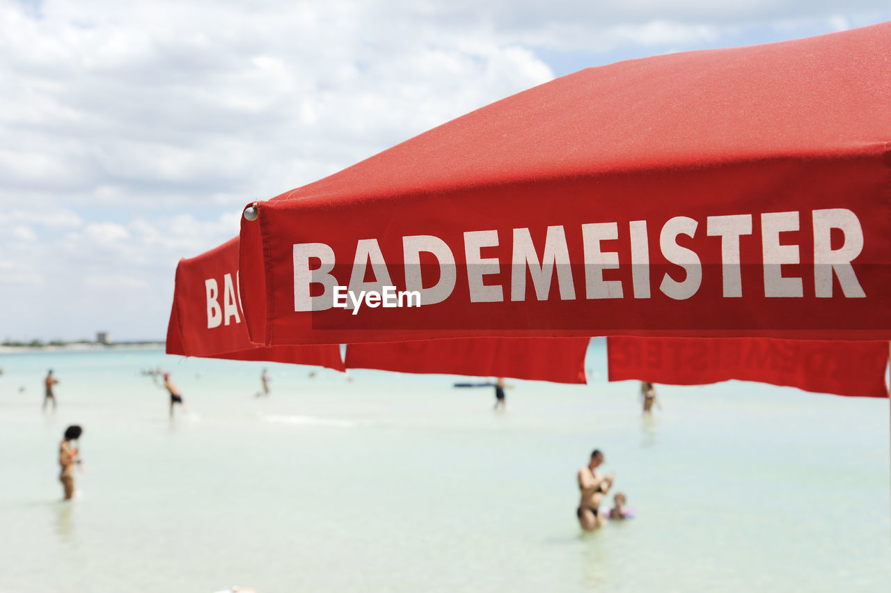 Close-up of text on umbrella against sea