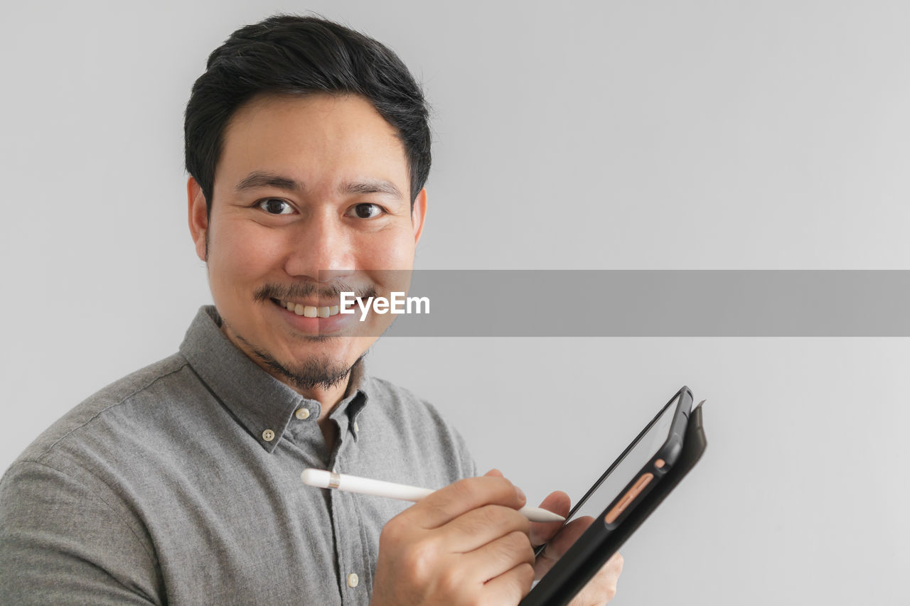 Portrait of businessman using digital tablet against white background