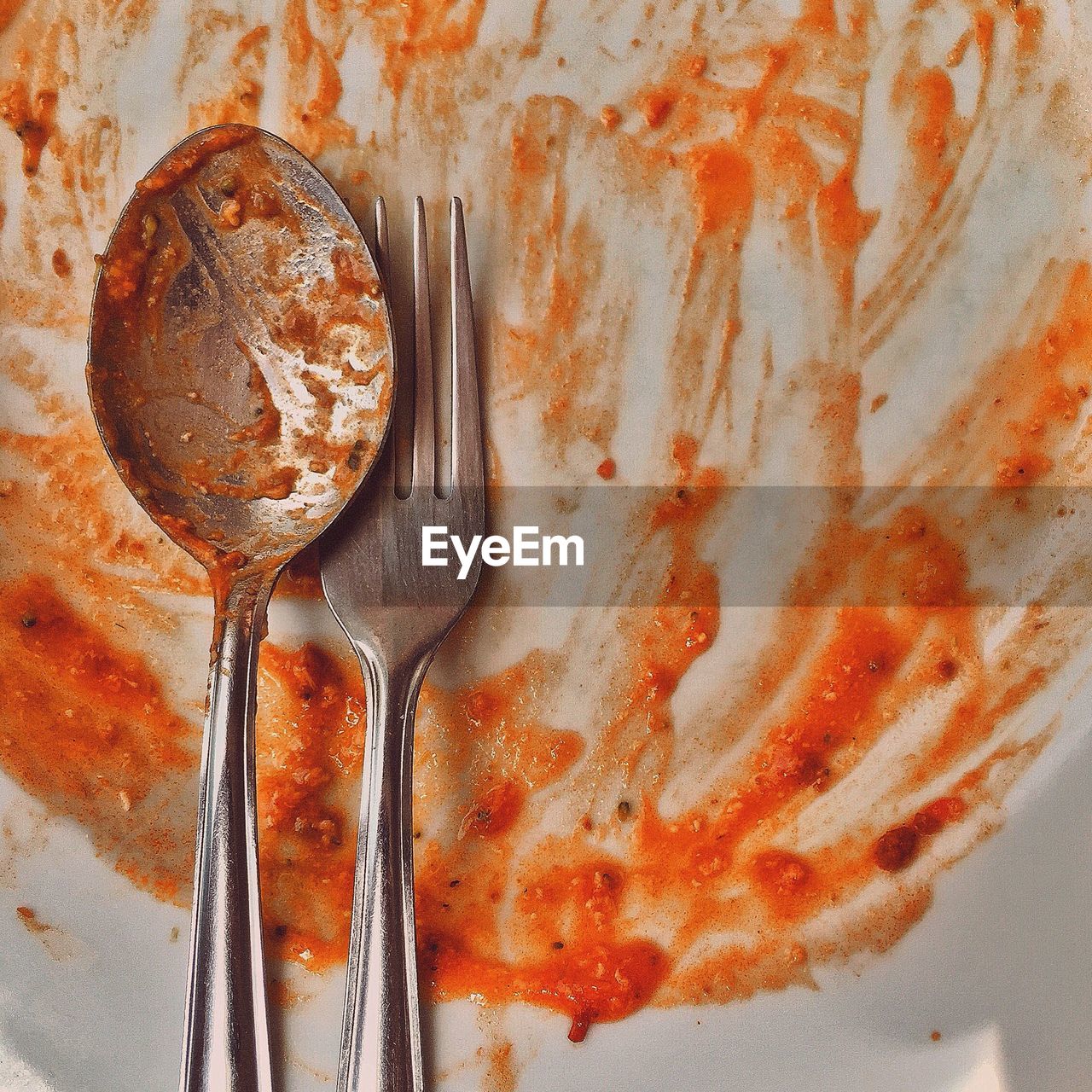 Close-up of spoon and fork in messy food plate