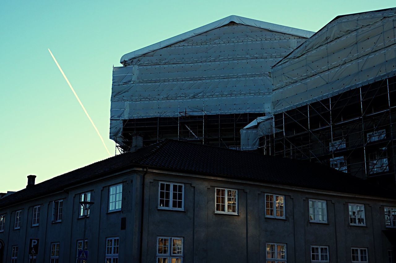 Low angle view of building with vapor trail