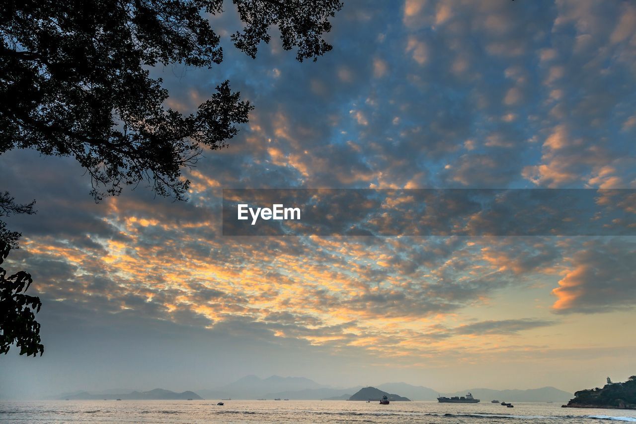 SCENIC VIEW OF BEACH AGAINST DRAMATIC SKY