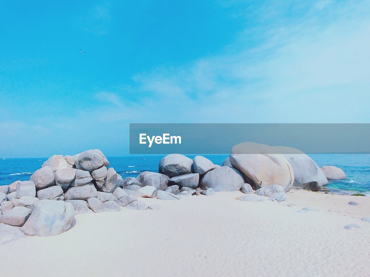 Rocks on beach against blue sky