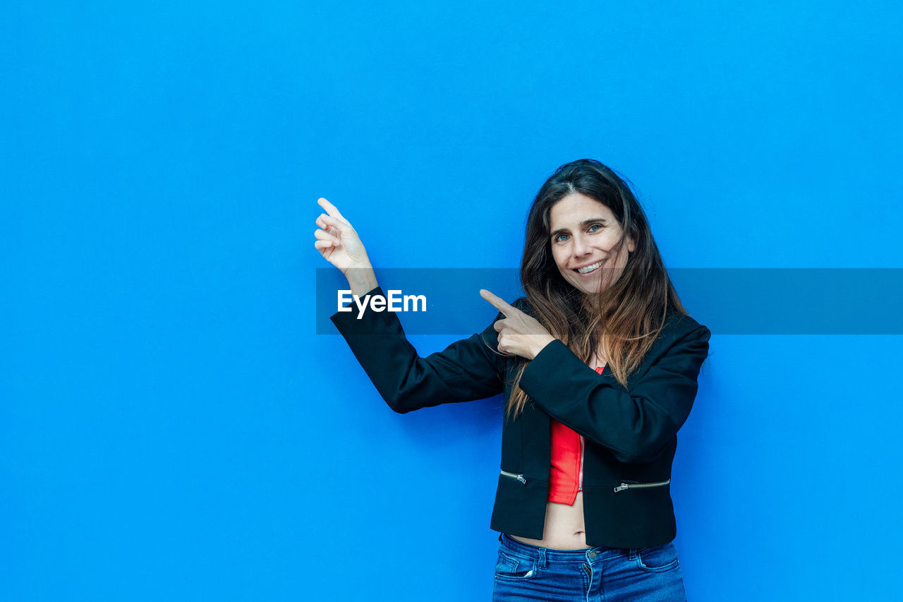 WOMAN STANDING AGAINST BLUE WALL