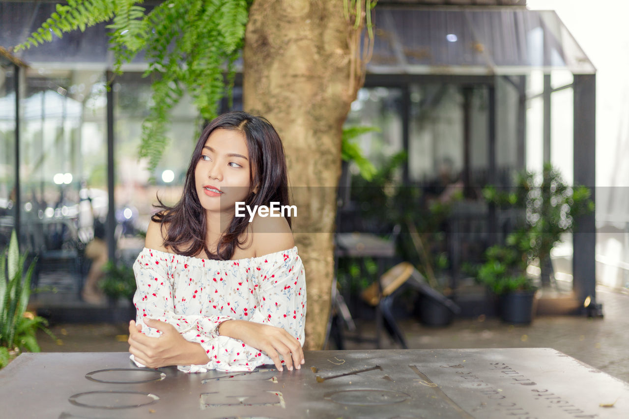 Biracial women thinking at a table in a coffee shop.