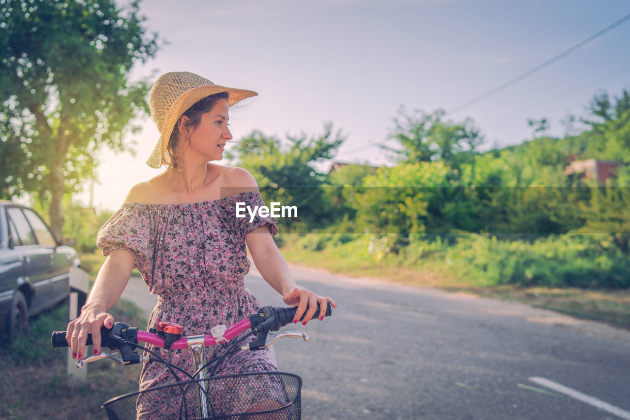 Woman looking away while riding bicycle on road