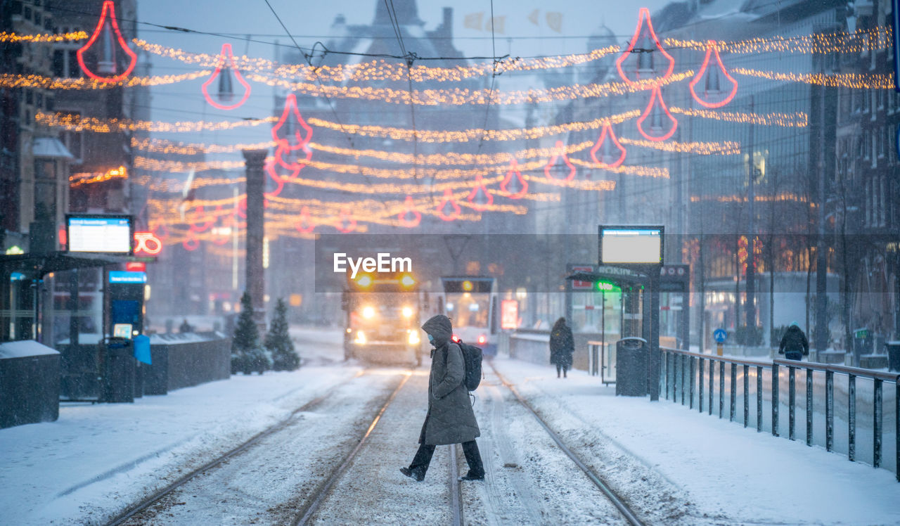 Woman walking on snow covered city street during winter