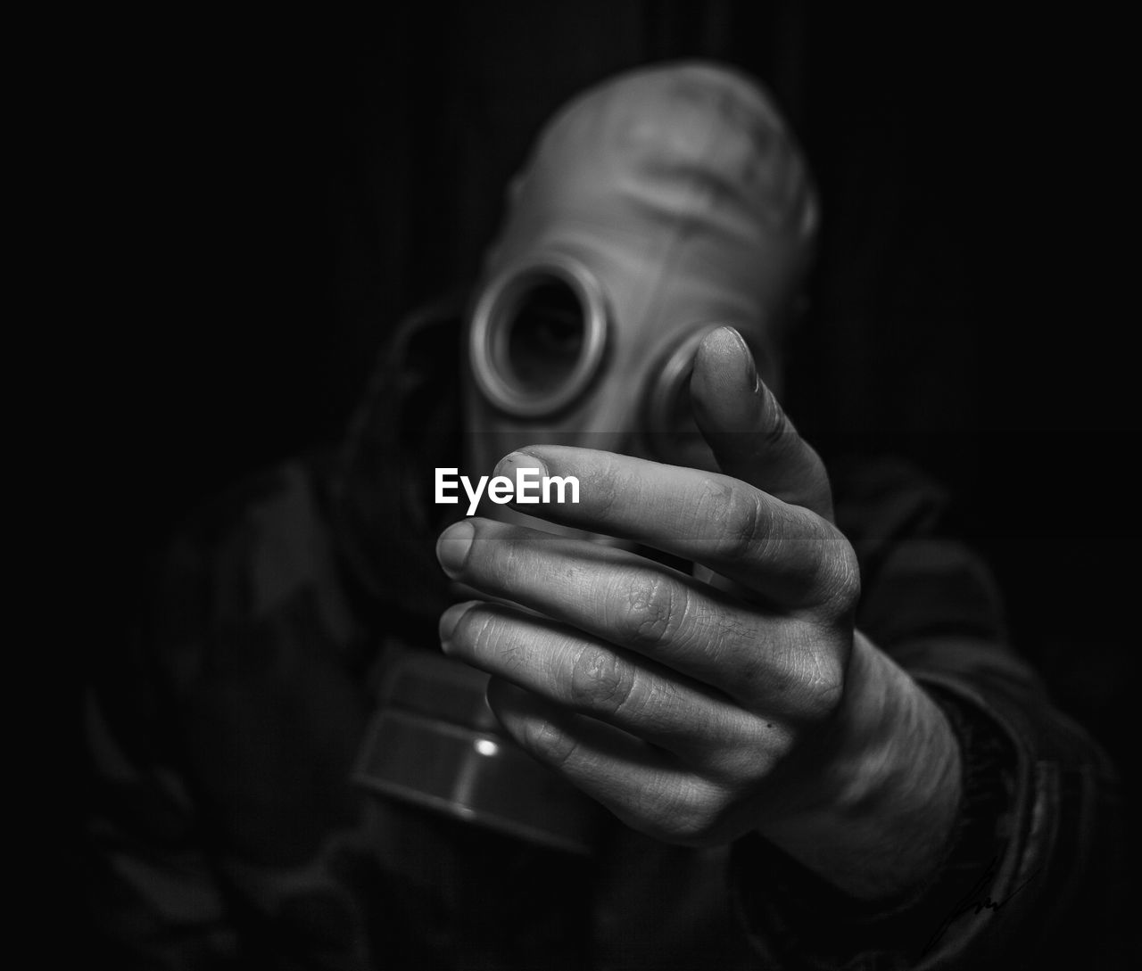 Close-up of man holding gas mask against black background