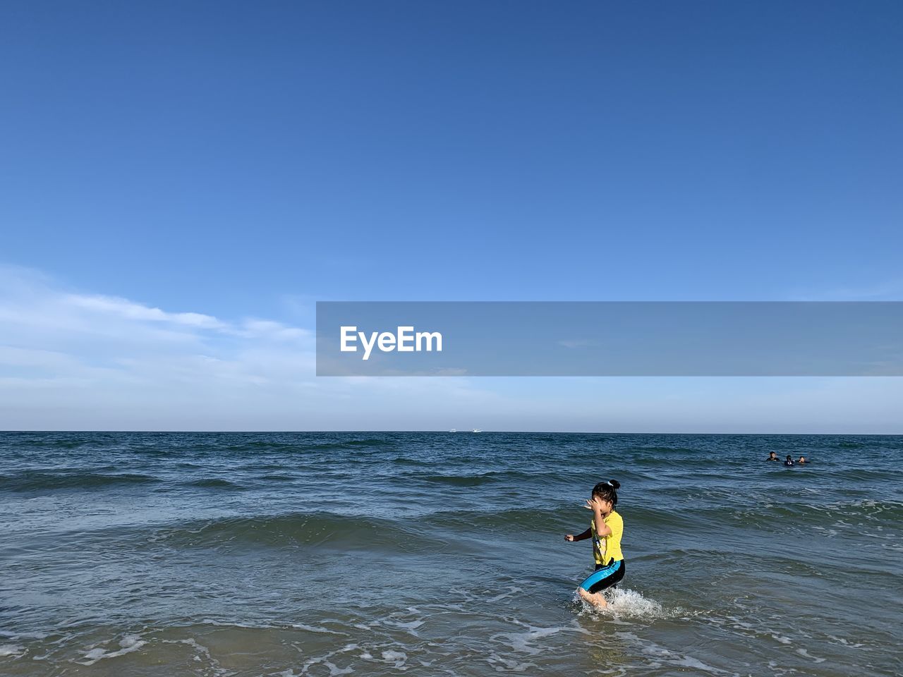 Smiling girl standing at shore against sky