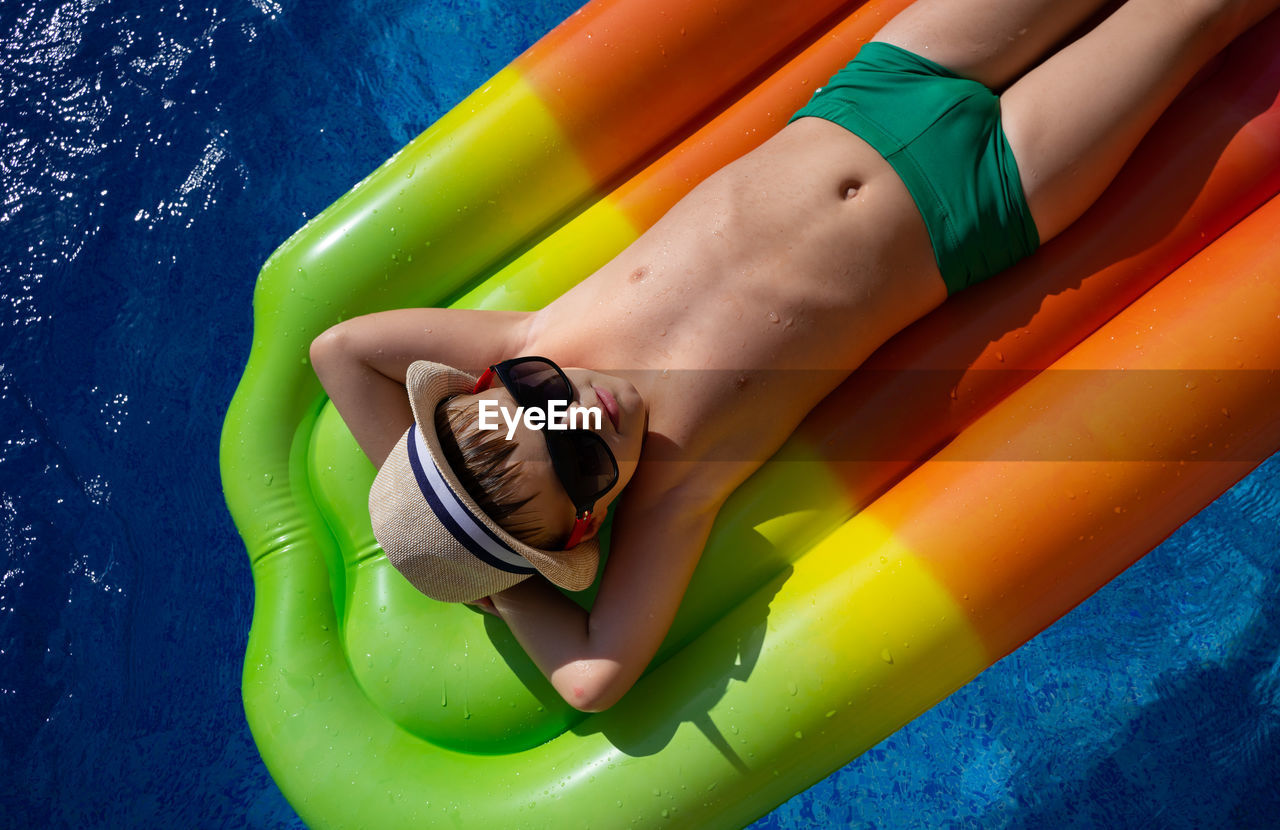 Boy in a straw hat swims in the pool on an inflatable mattress. bright juicy summer photo