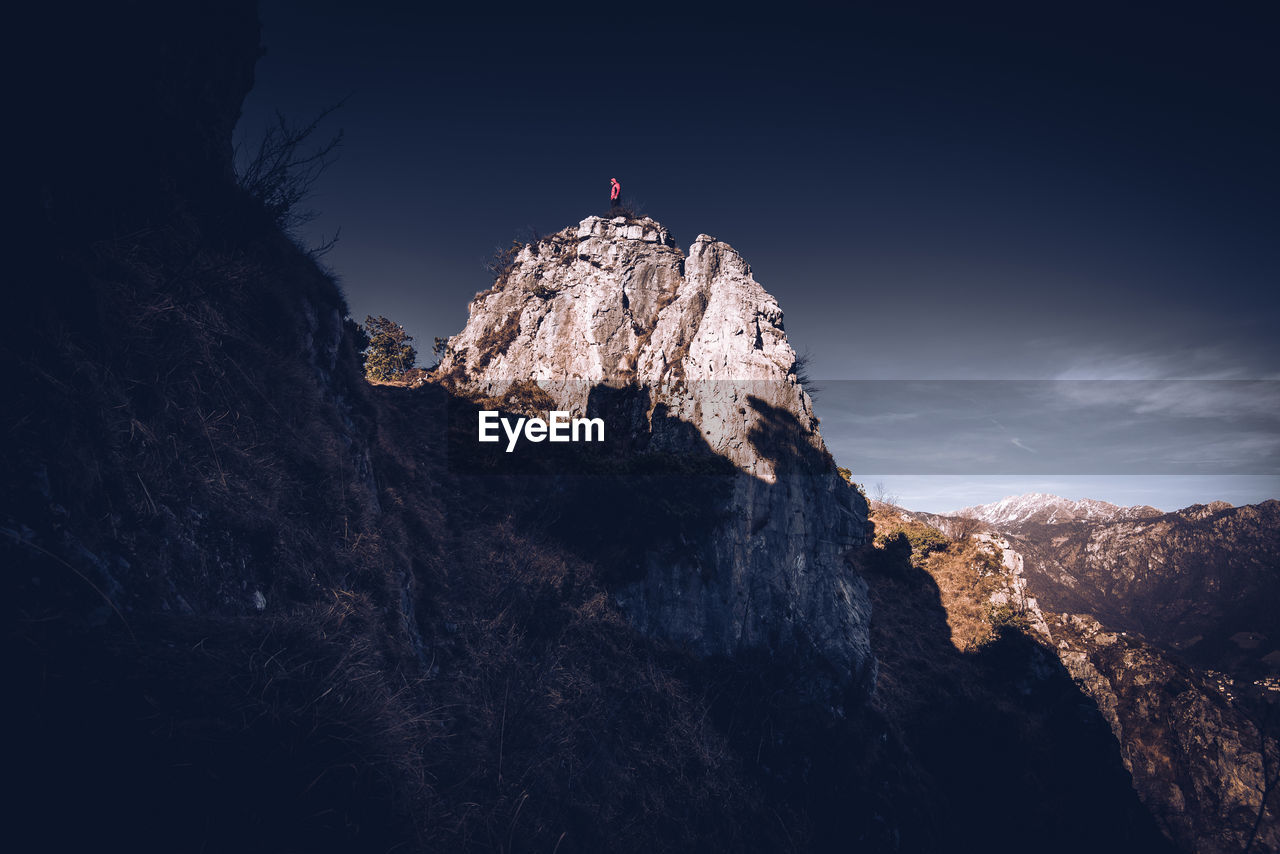 Low angle view of person on rock against sky