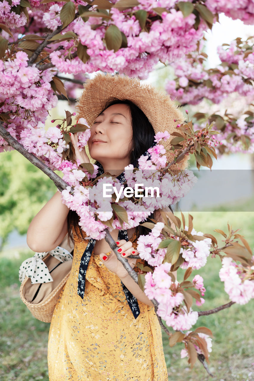Young japanese woman wearing hat among cherry trees