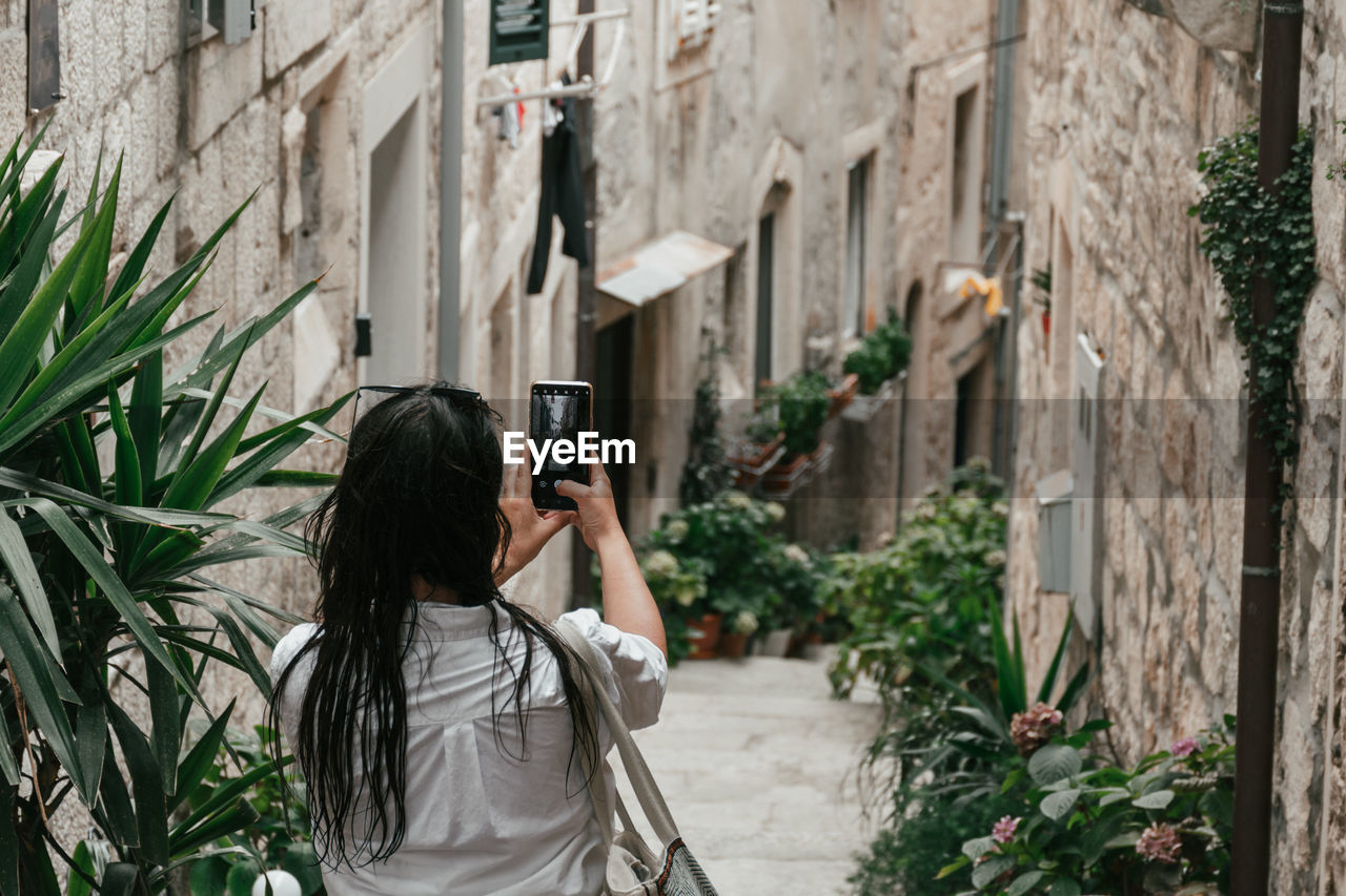 Woman taking photos in narrow street of idyllic old town in korcula, croatia.