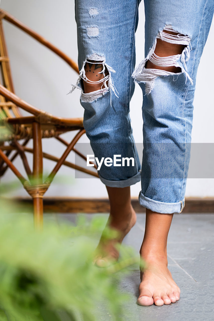 Bare feet woman wearing ripped jeans on terrace.
