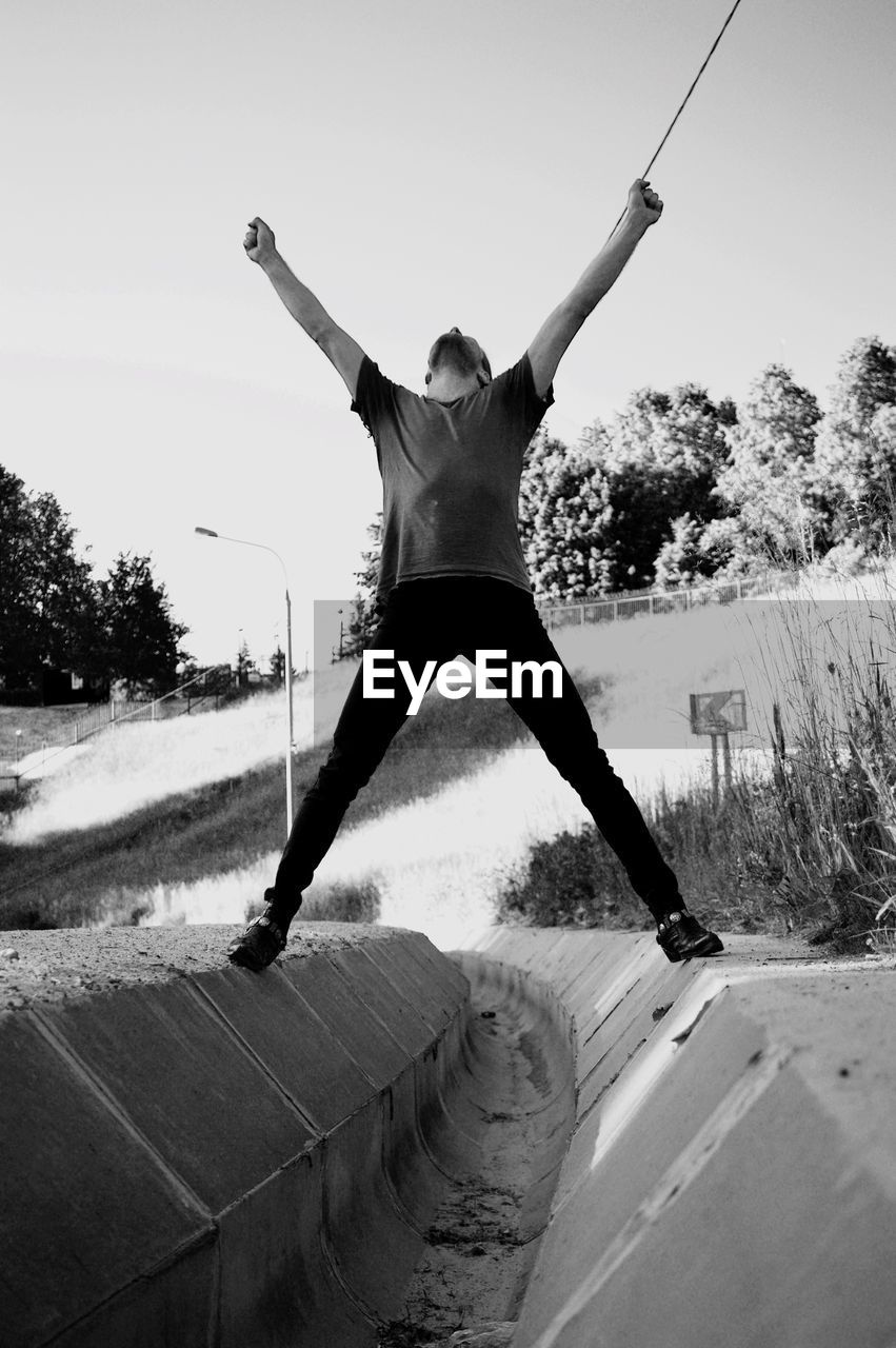 LOW ANGLE VIEW OF MAN JUMPING ON TREE