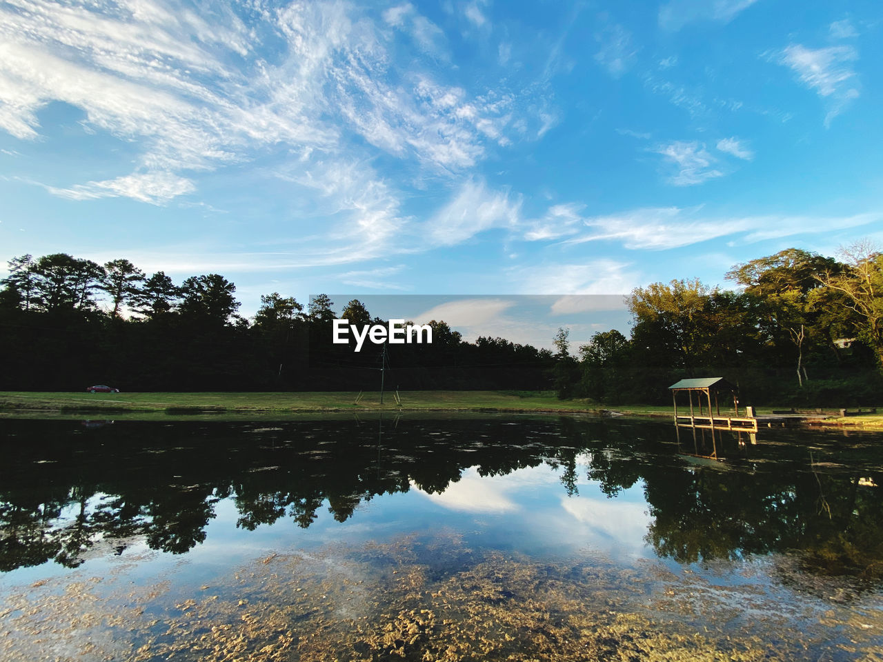 REFLECTION OF TREES ON LAKE AGAINST SKY