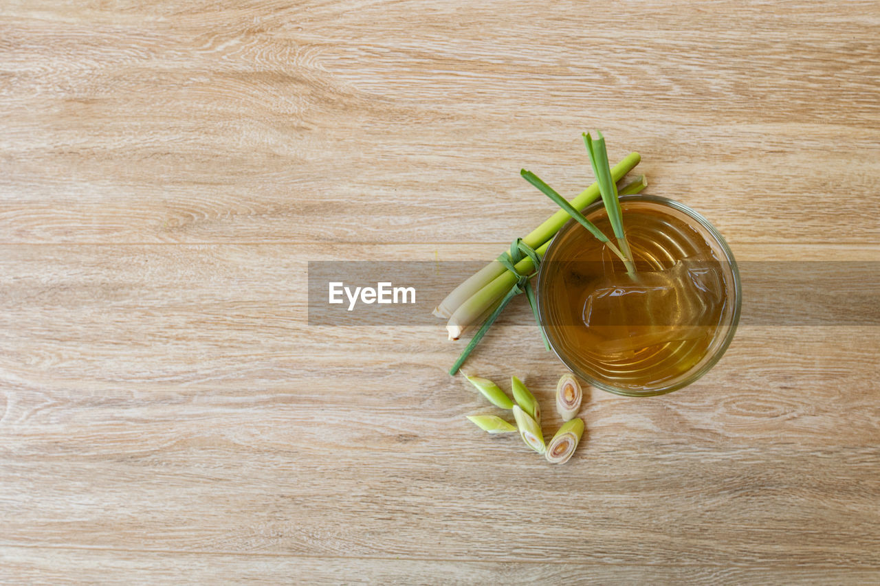 Sweet lemon grass juice in a glass is placed on a light brown table. top view 