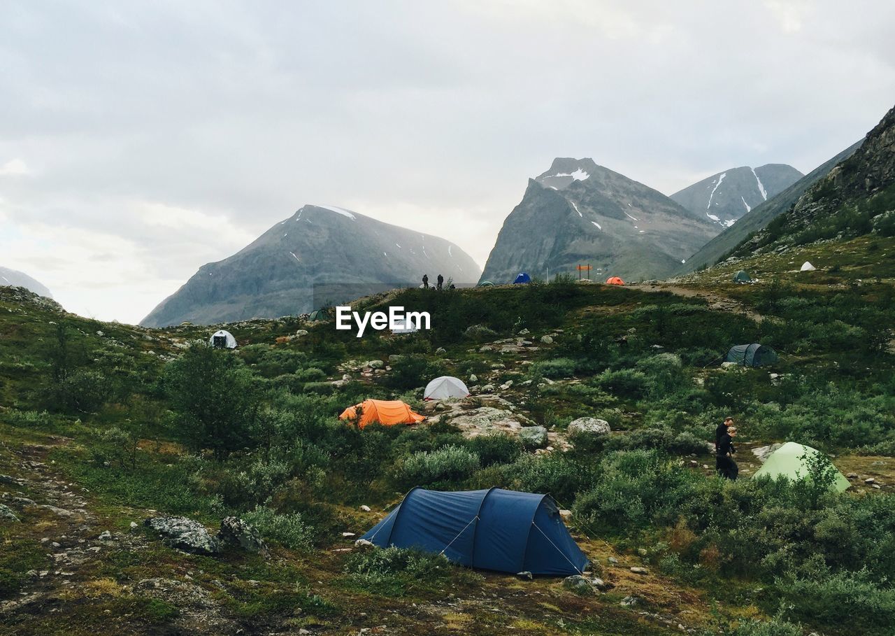 Scenic view of landscape, mountains against sky and camping tents on the hills