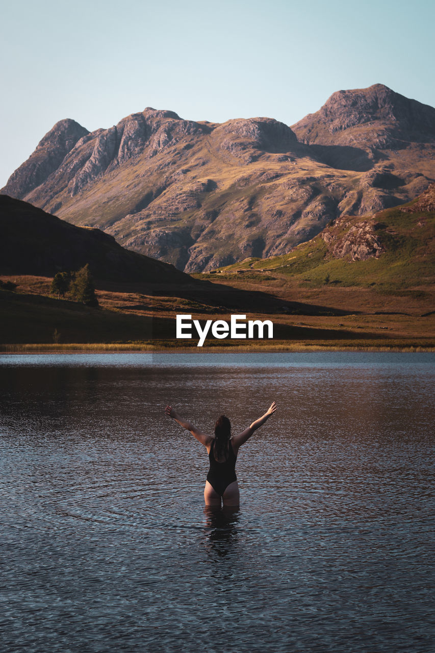 Rear view of woman l in lake against mountain range