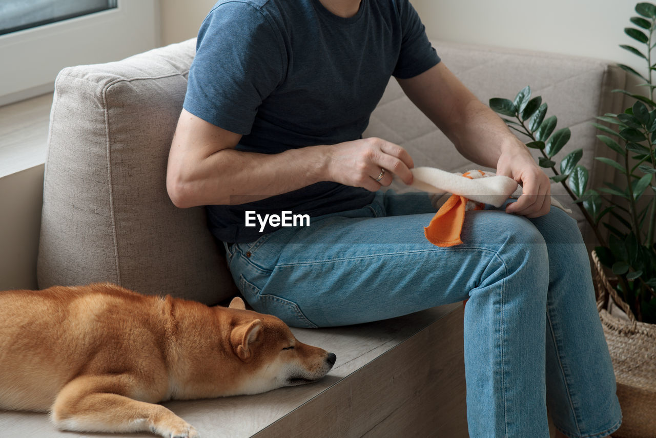 Adult man making diy homemade educational toys for dogs using a tutorial from the internet