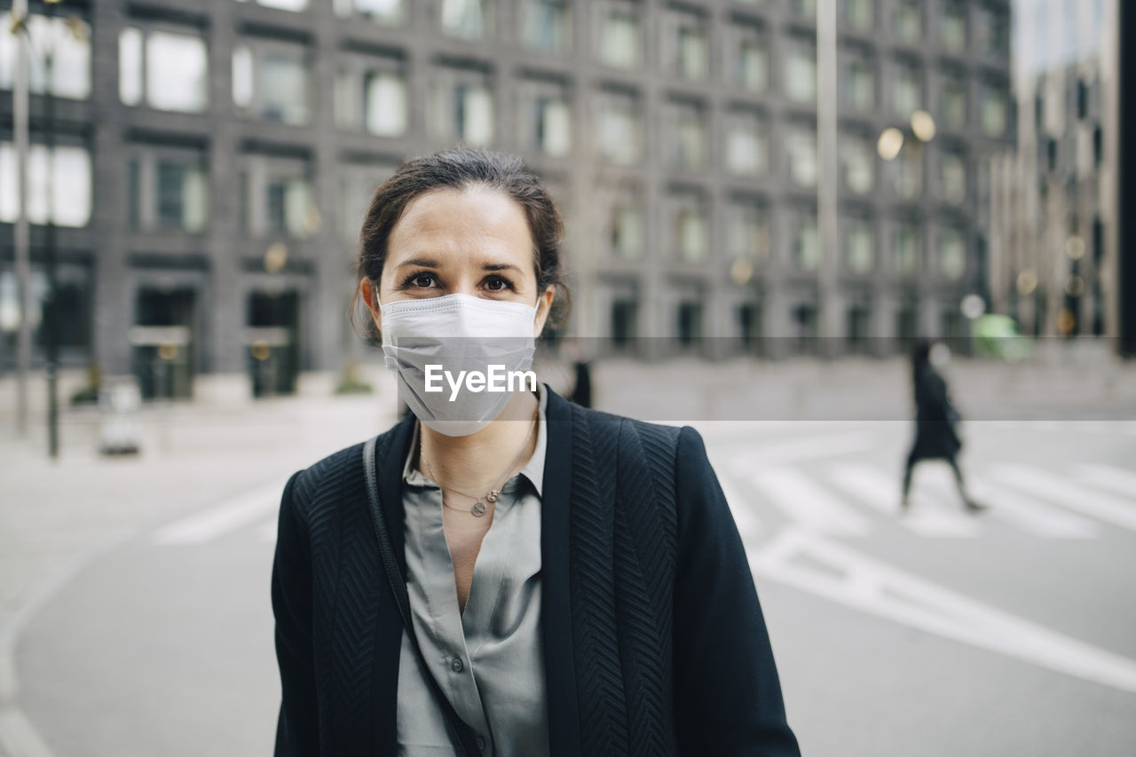 Portrait of female professional with protective face mask in city