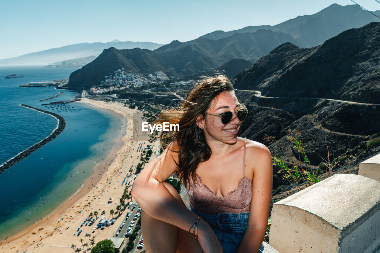 BEAUTIFUL YOUNG WOMAN IN SUNGLASSES ON BEACH