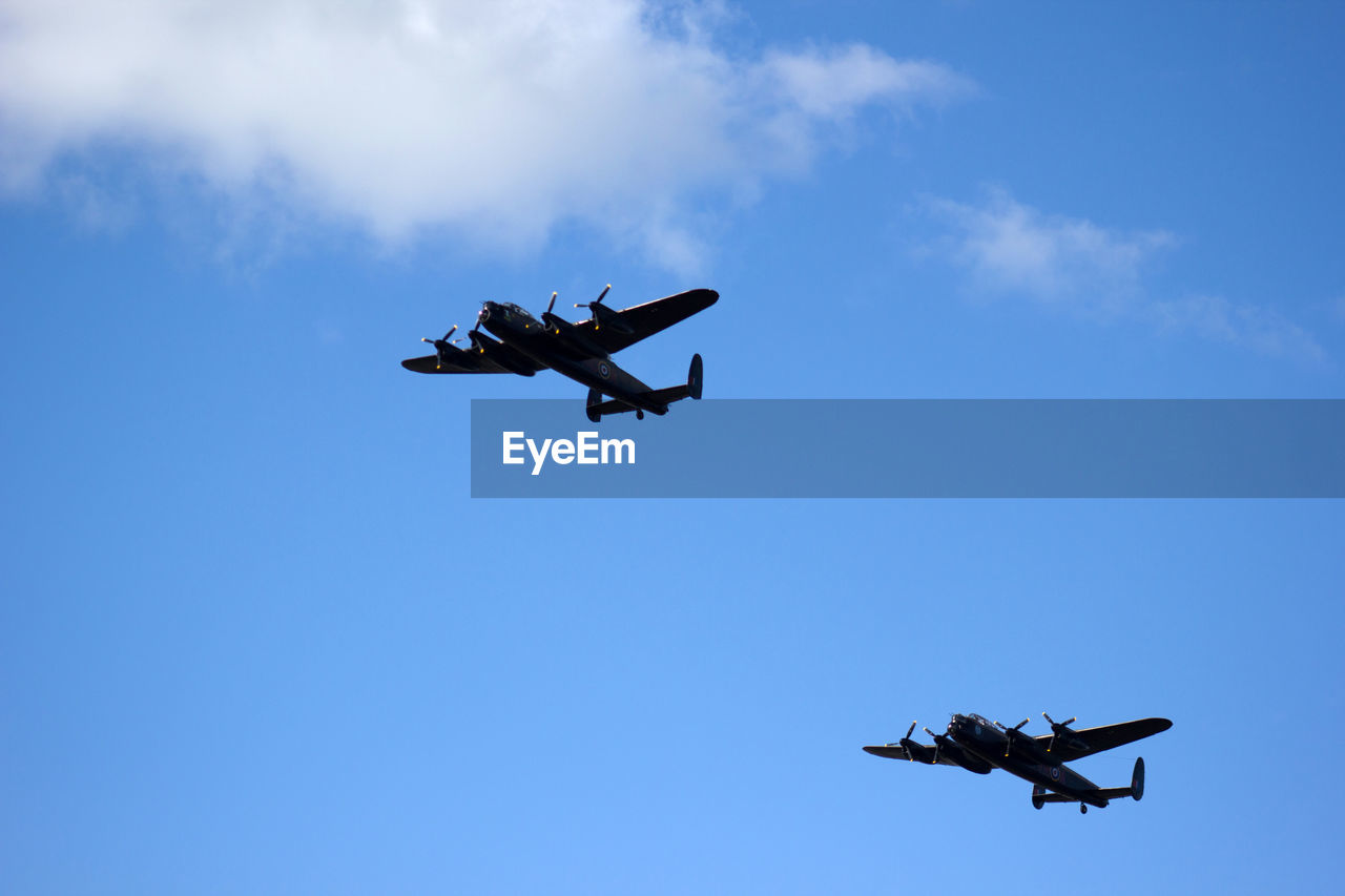 Low angle view of fighter airplane flying against blue sky