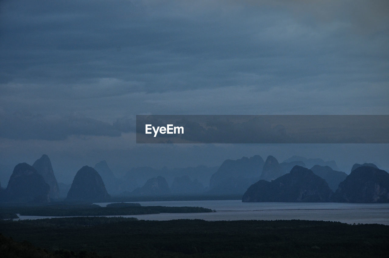 Scenic view of sea and mountains against sky at dusk