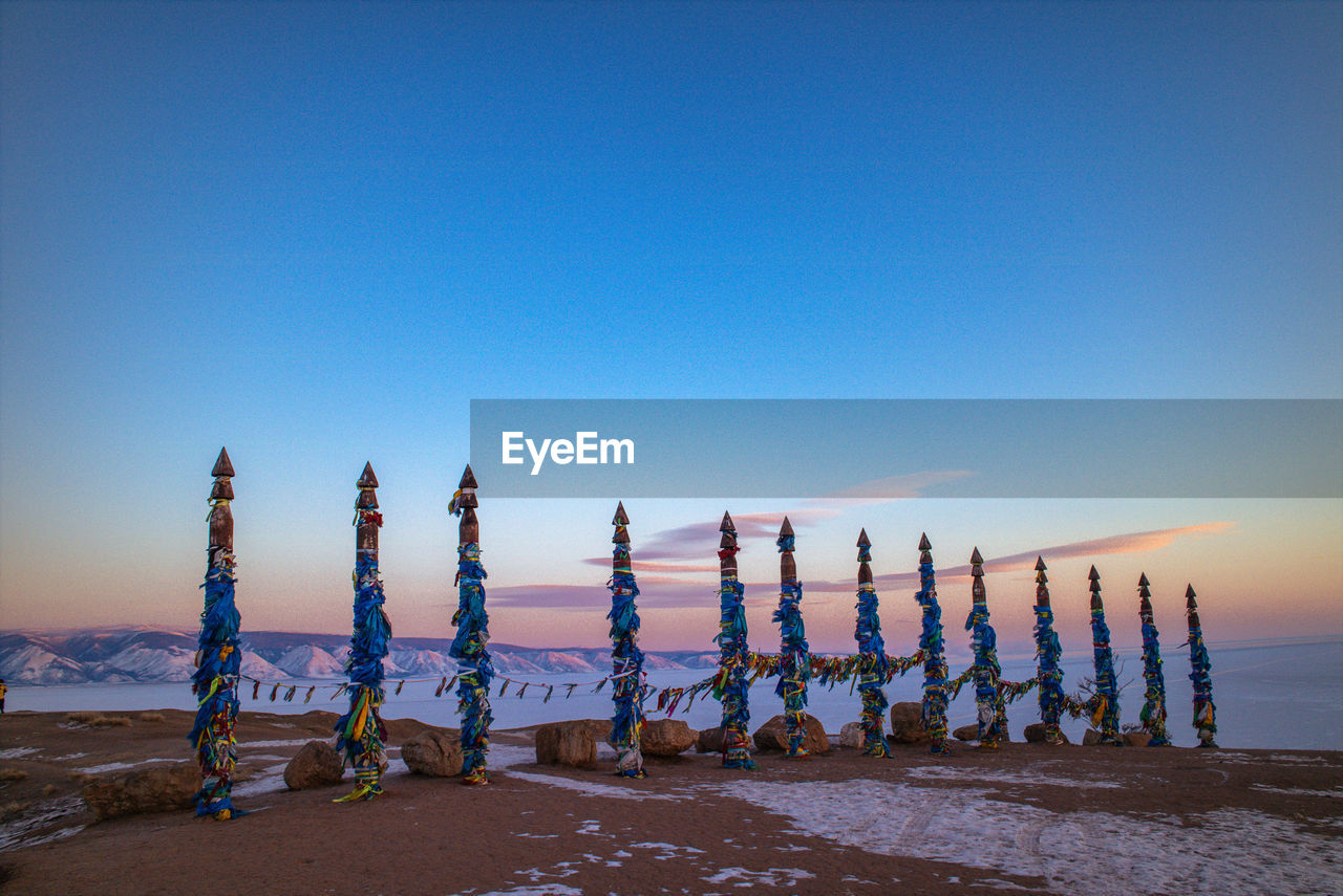 Multi colored prayer flags on bamboo poles at mountain against sky during sunset