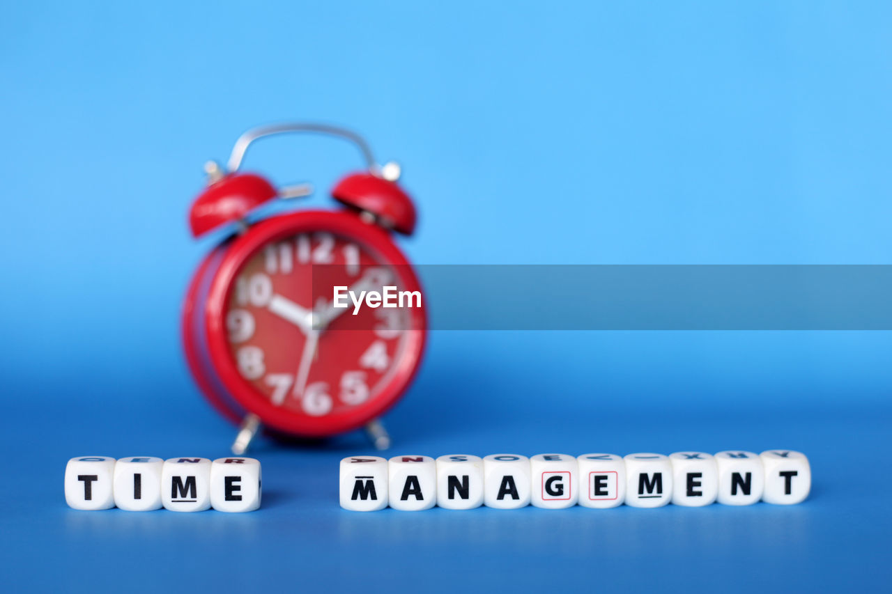 Time management conceptual with word block and clock on blue background