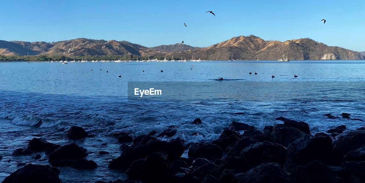 SCENIC VIEW OF SEA AGAINST MOUNTAINS