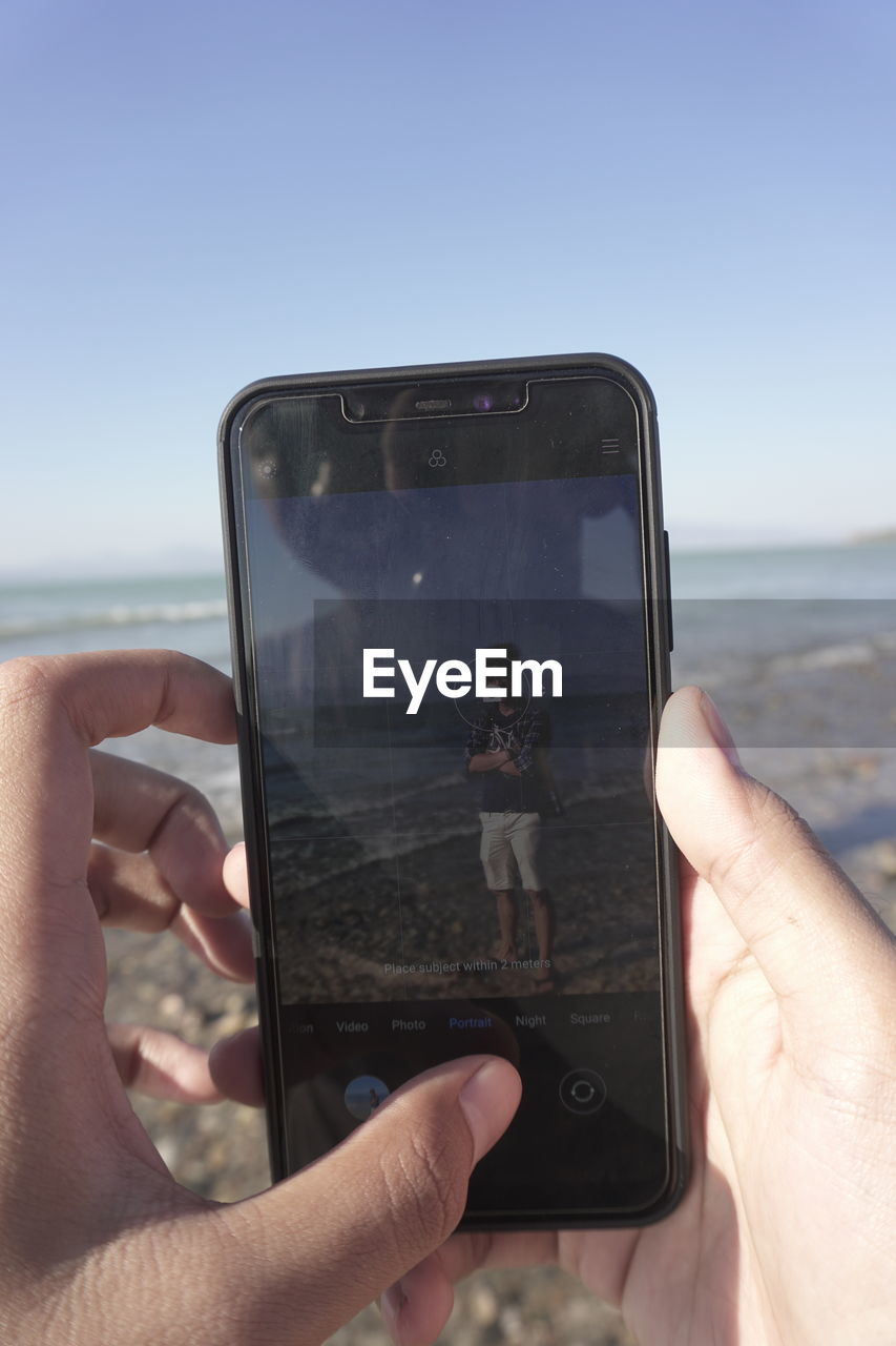 MIDSECTION OF PERSON PHOTOGRAPHING SEA