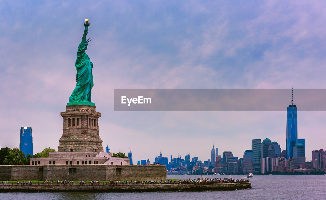 Statue of liberty against cityscape and sky during sunset