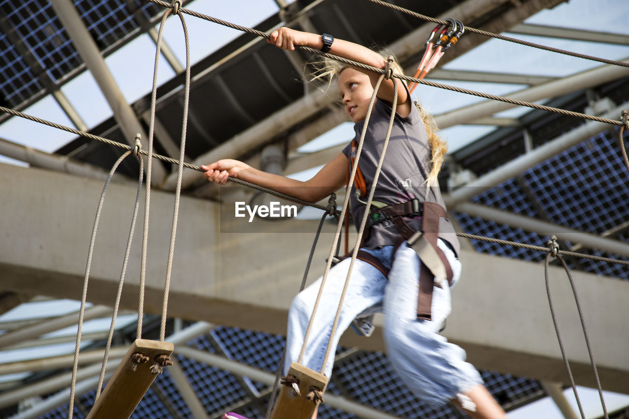 Low angle view of girl climbing rope