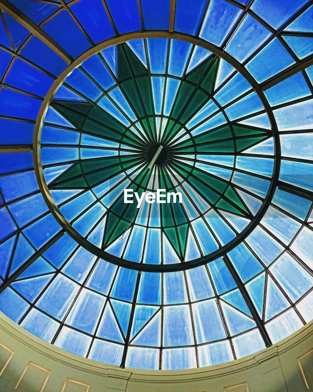 dome, daylighting, architecture, built structure, ceiling, glass, pattern, geometric shape, low angle view, skylight, indoors, shape, no people, circle, architectural feature, blue, directly below, day, sky, window, transparent, sunlight, roof, building, backgrounds, full frame, shopping mall, travel destinations