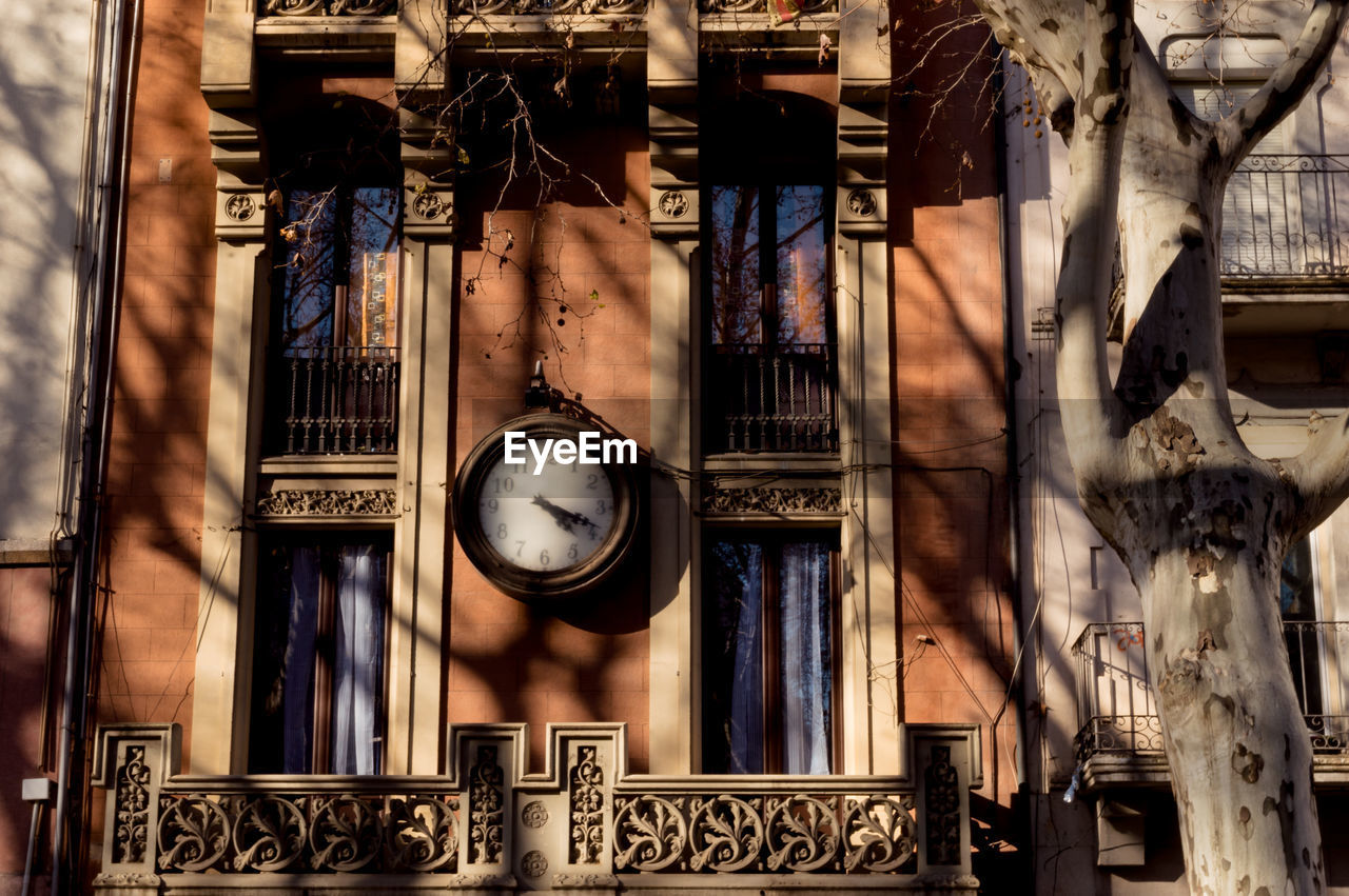 LOW ANGLE VIEW OF CLOCK HANGING IN OLD BUILDING