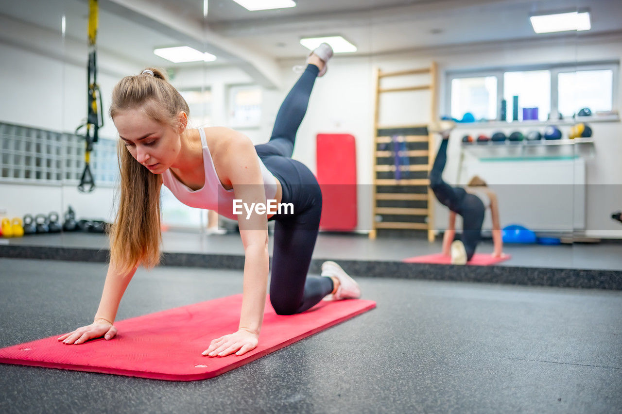 full length of young woman exercising in gym