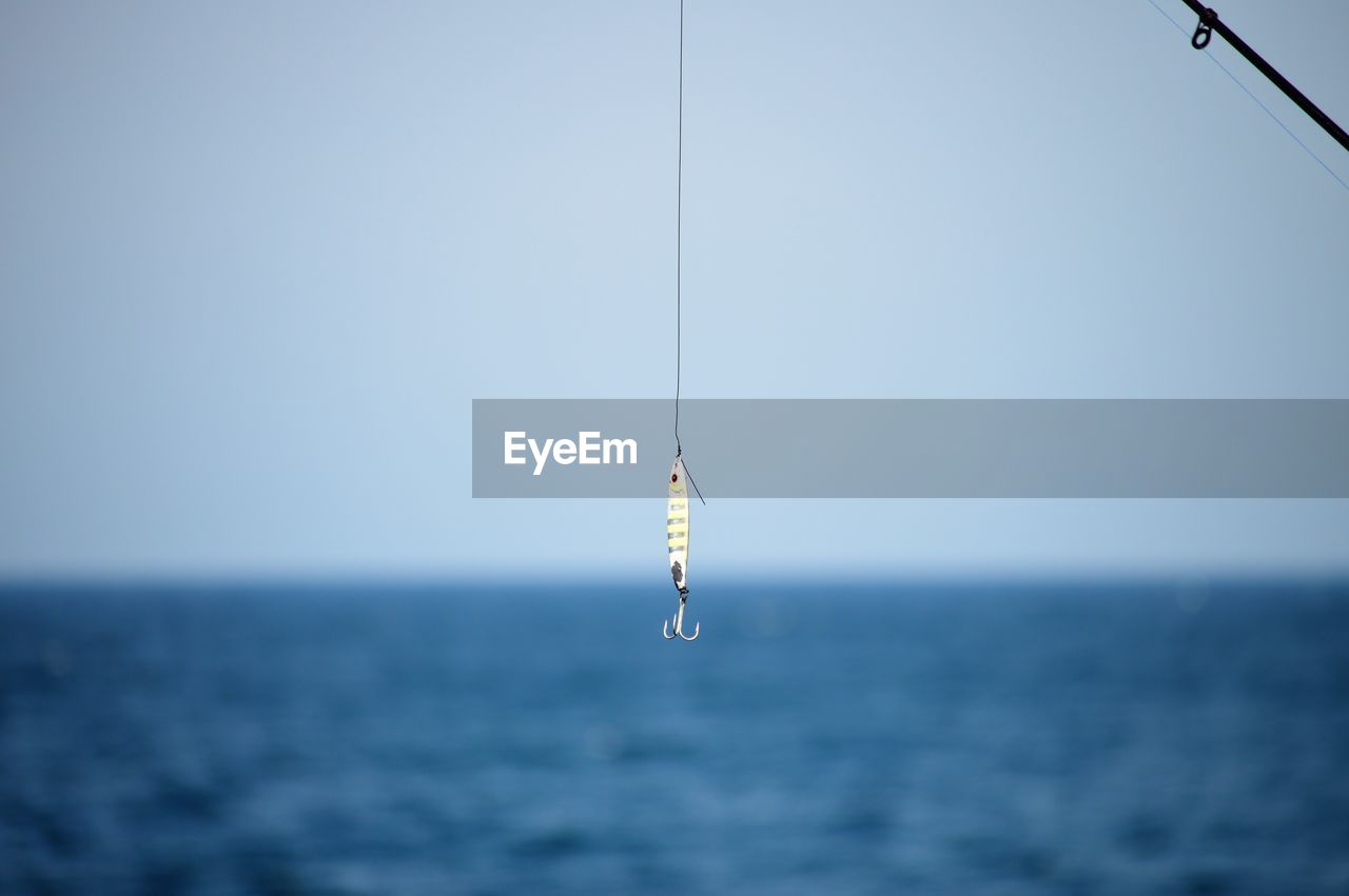 Fishing rod on sea against clear sky