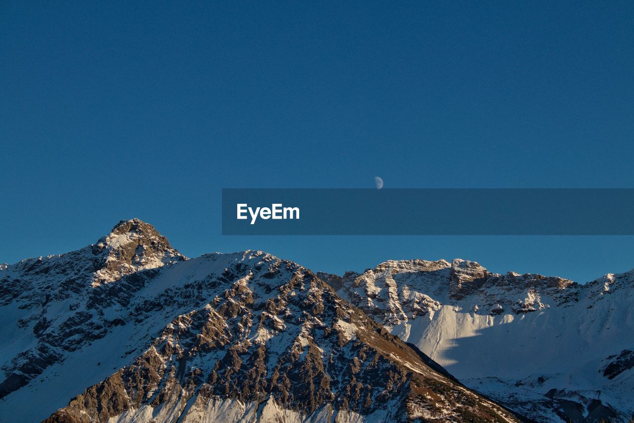 Scenic view of snowcapped mountains against clear blue sky