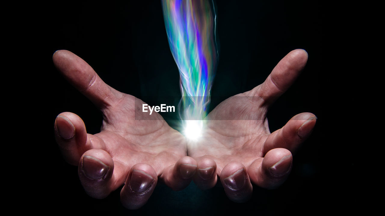 CROPPED IMAGE OF HAND HOLDING OVER BLACK BACKGROUND