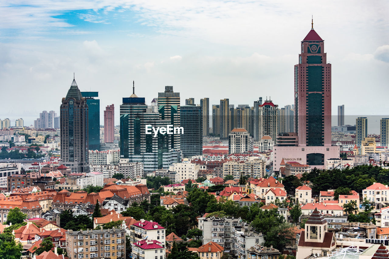 Buildings in city against cloudy sky