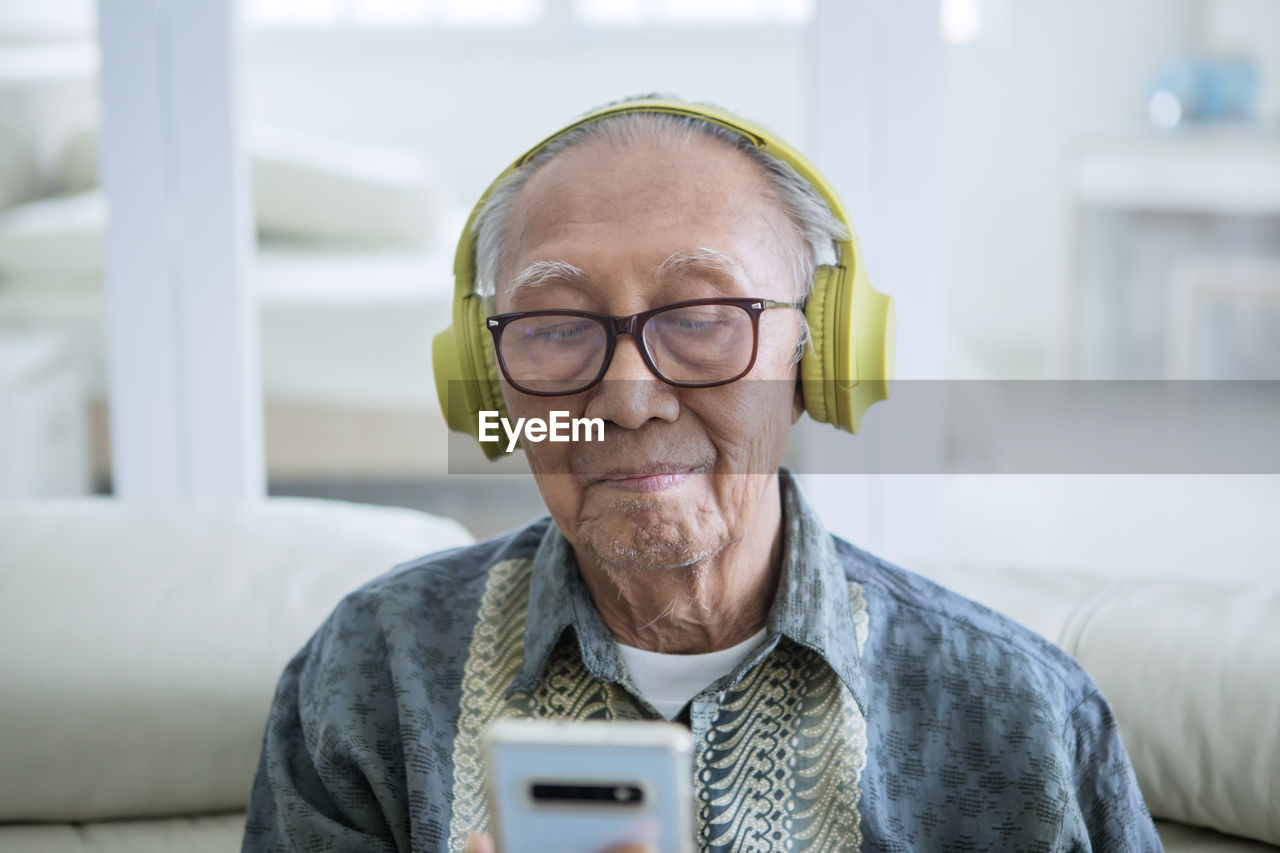 Man listening music through headphones sitting at home